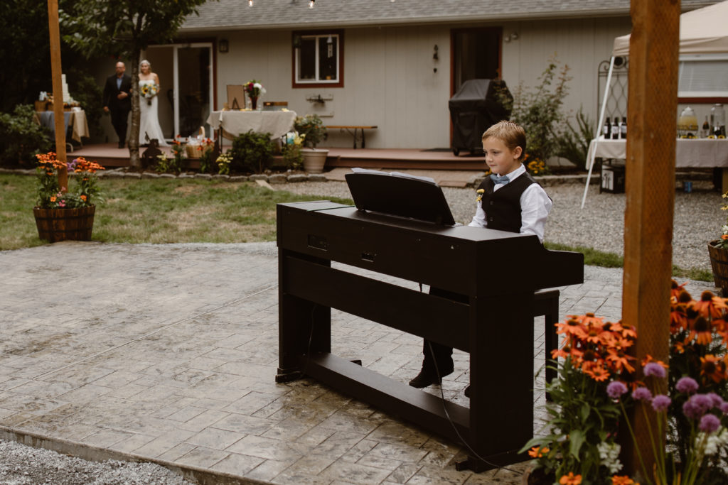 Son playing piano as bride walks down the aisle.