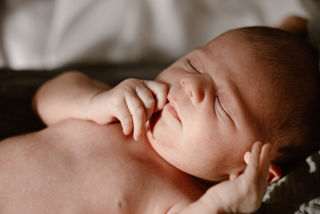 Newborn baby sleeping with hands near face