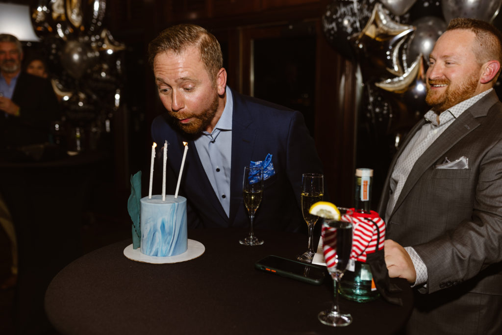 Candid of birthday man blowing out candles at a 40th birthday party
