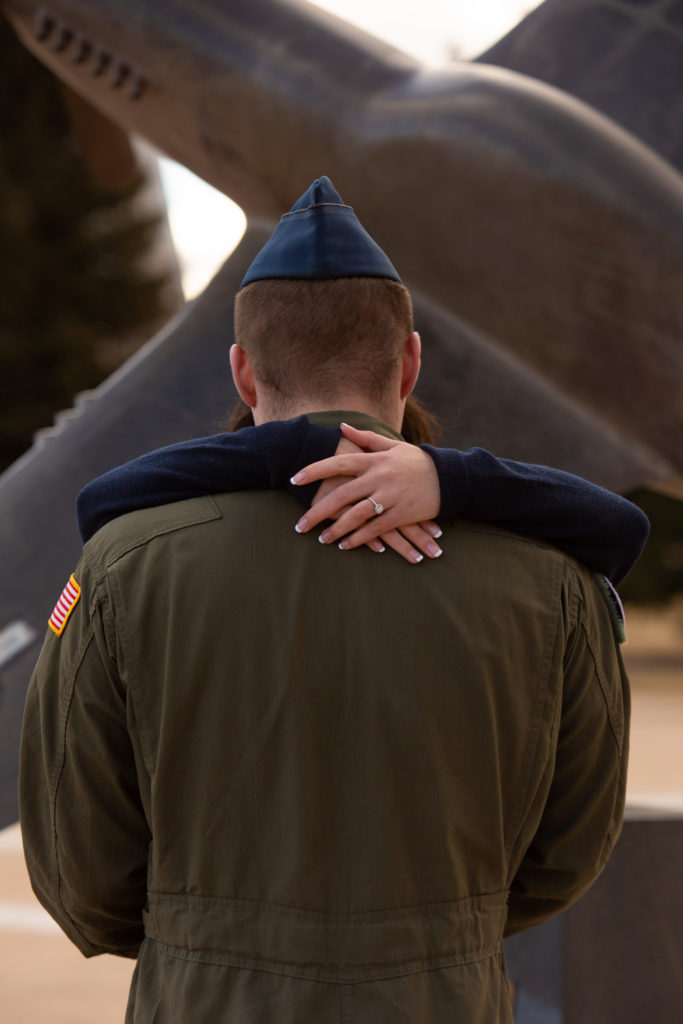 Man in Air Force uniform with his fiancé's arms around his neck