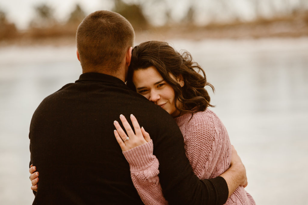Woman hugging her fiancé, looking at the camera over his shoulder