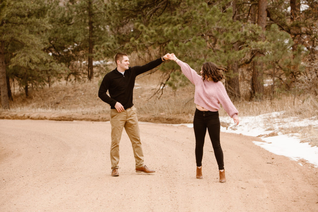 Man spinning his fiancé on a dirt road