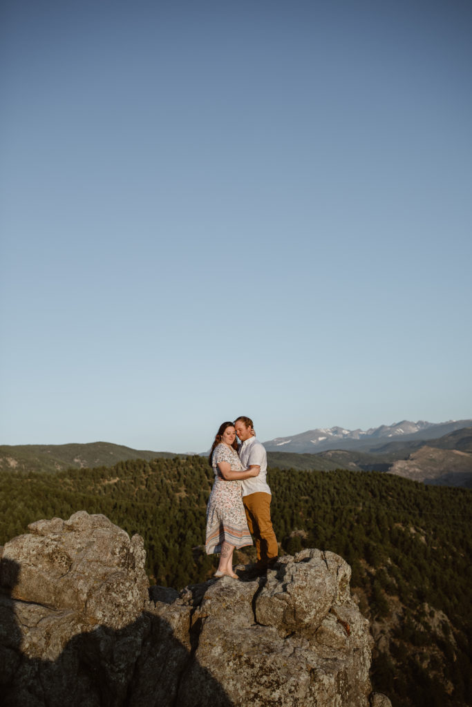 Couple with arms around each other on a rock in the mountains