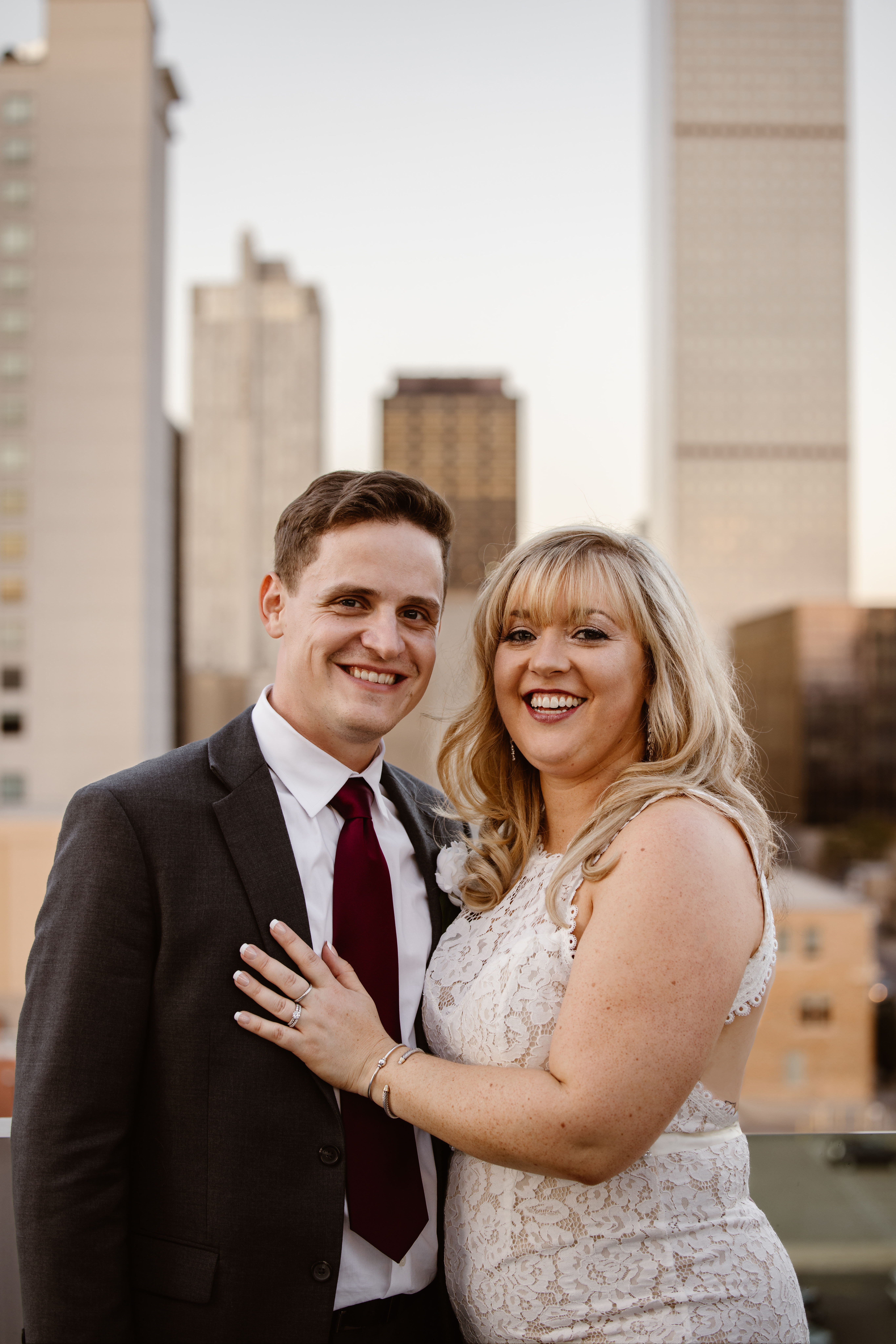 Portrait of groom and bride on a rooftop with the city behind them
