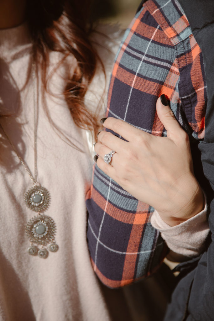Woman's hand with engagement ring holding her fiancé's arm