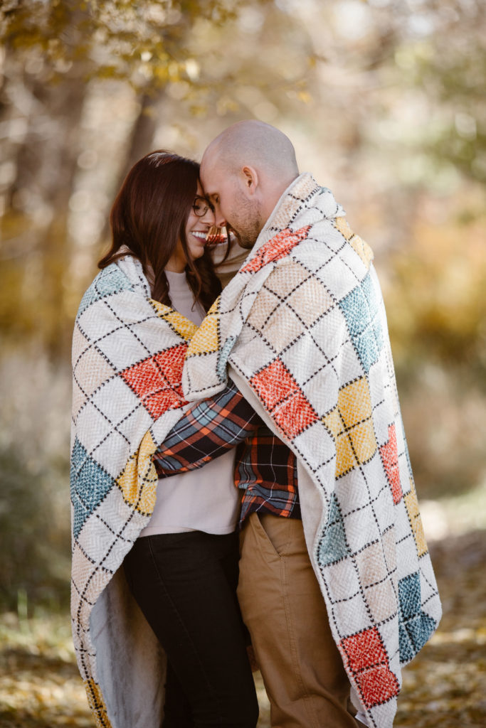 Couple facing each other cuddled with a blanket around them