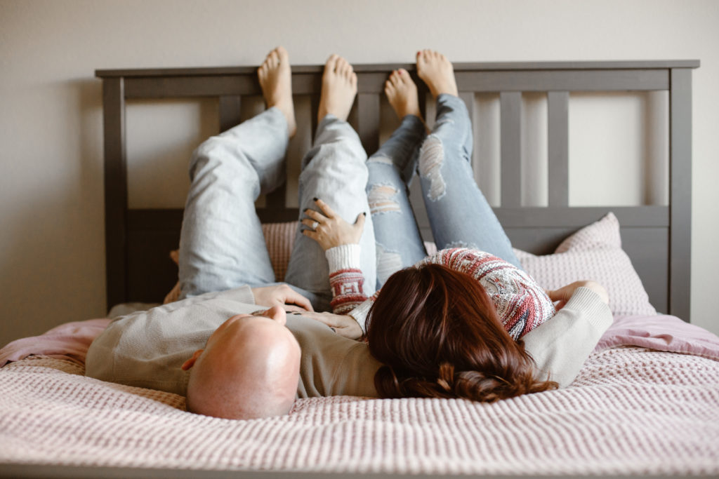 Couple laying on their bed with their feet on the headboard