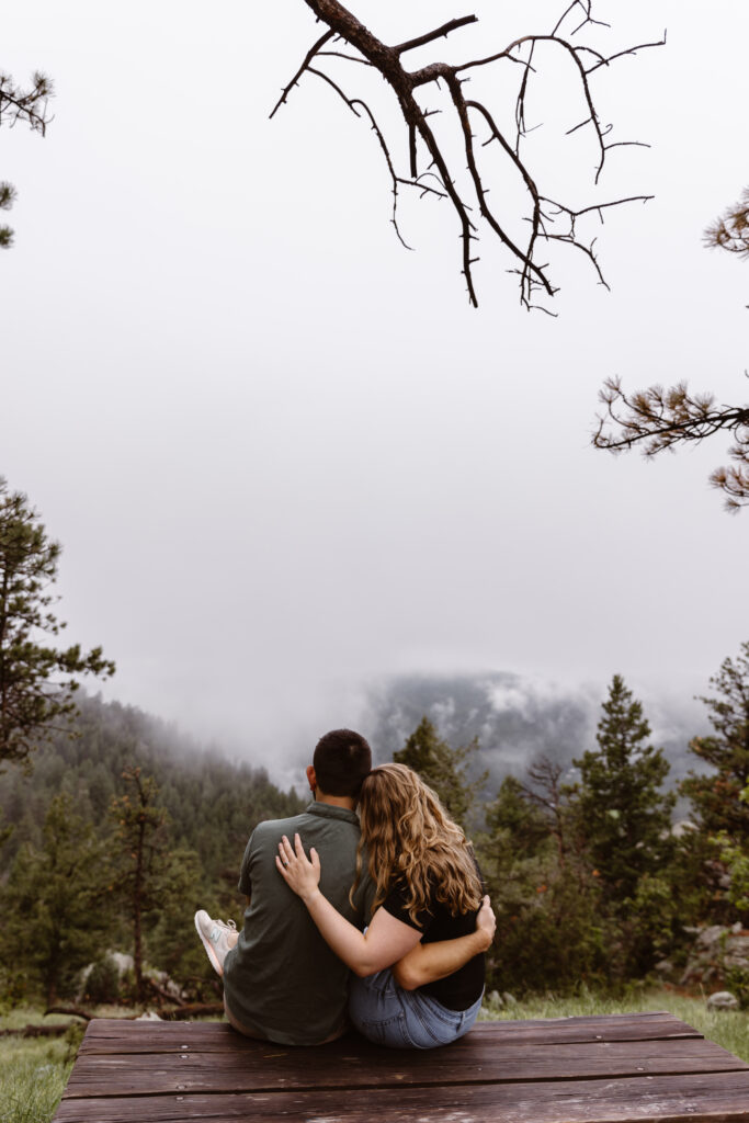 Couple cuddled up on a picnic table looking at the view