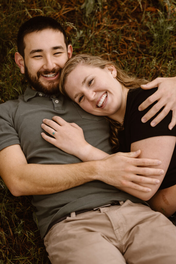 Couple laying on the ground cuddled up smiling