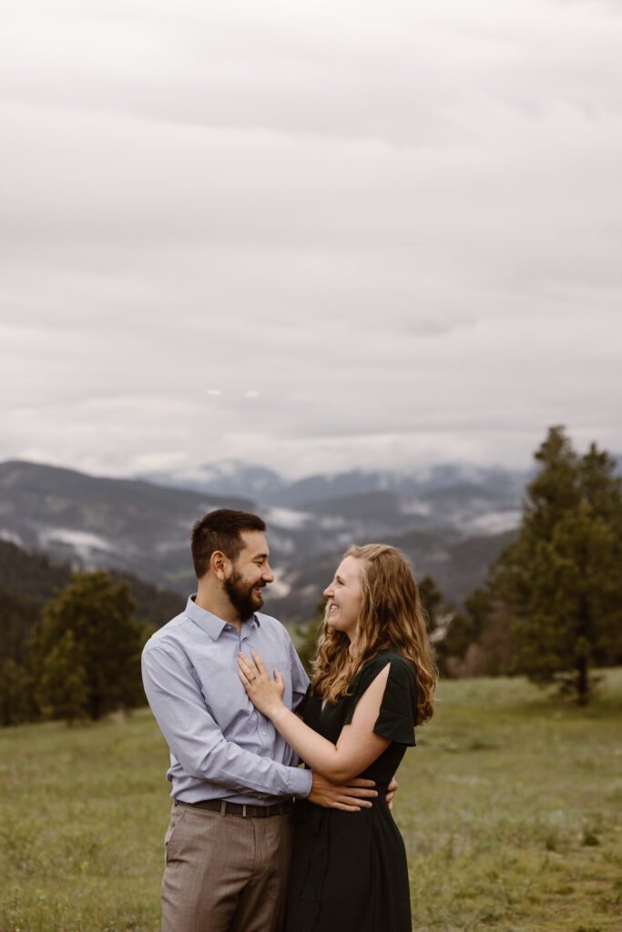 Engaged couple looking at each out with the mountains in the background