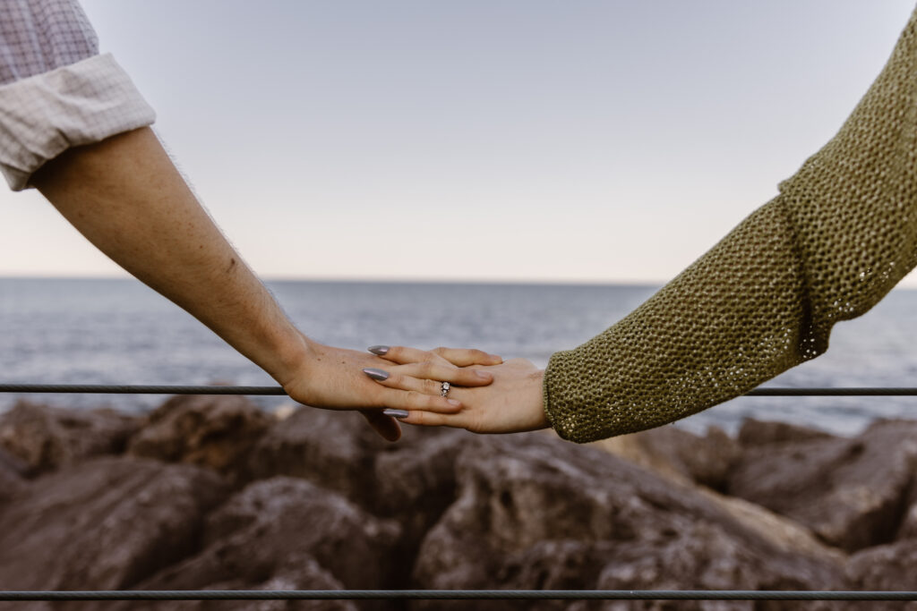 Close up on couple's hands with a lake in the background