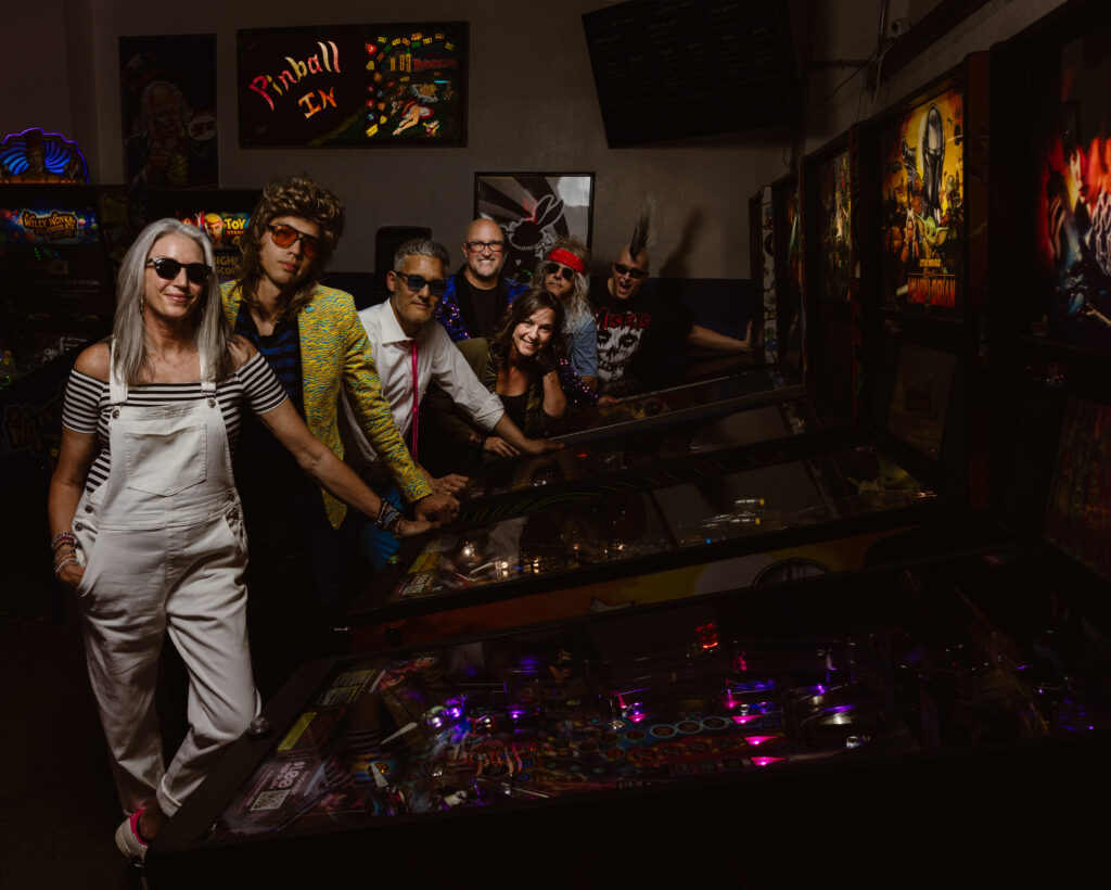 Full band portrait in front of old arcade games