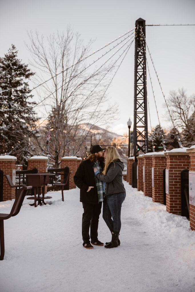 Couple share a kiss on a snowy sidewalk