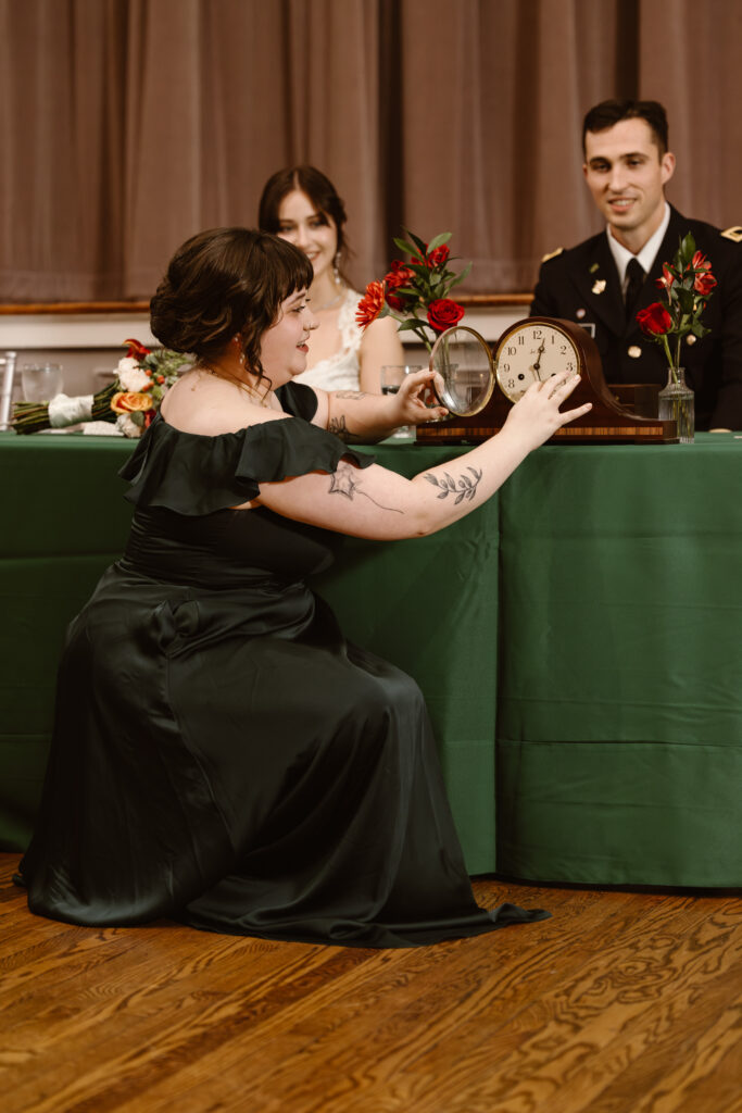 Maid of honor changing the time on a clock in front of the bride and groom