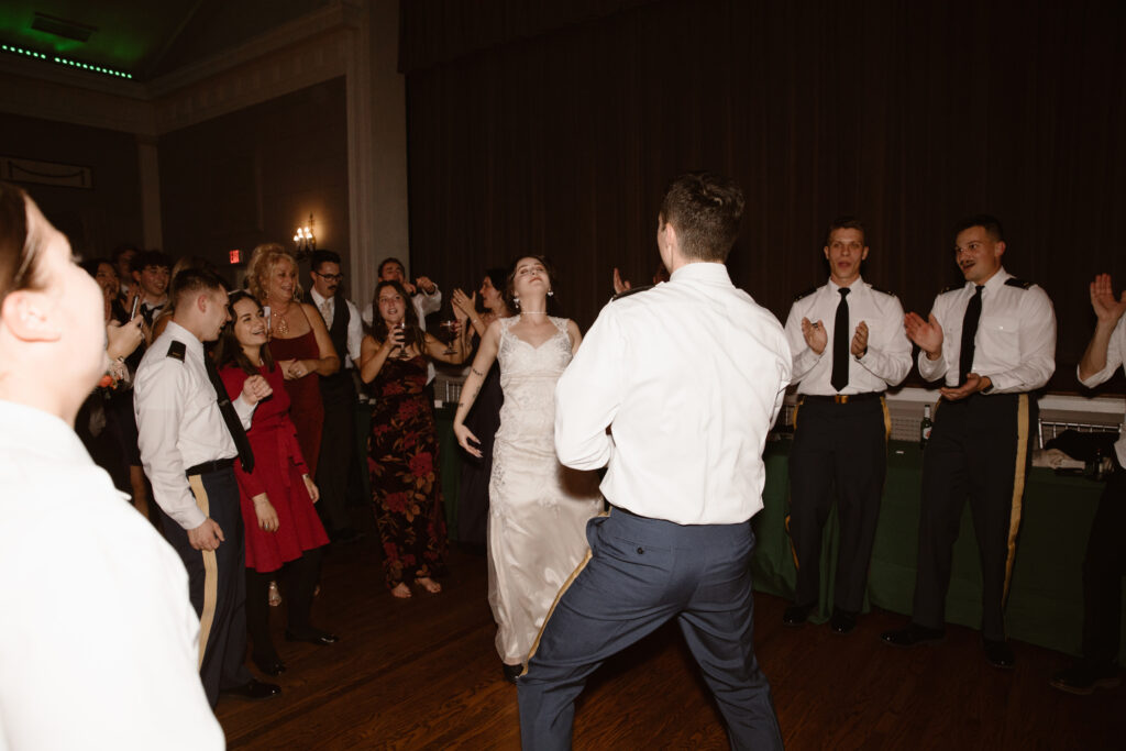 Bride and groom dancing during their reception surrounded by their friends cheering them on