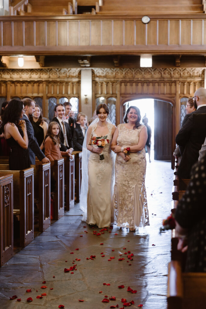Bride walking down the aisle of a church with her mom holding her arm