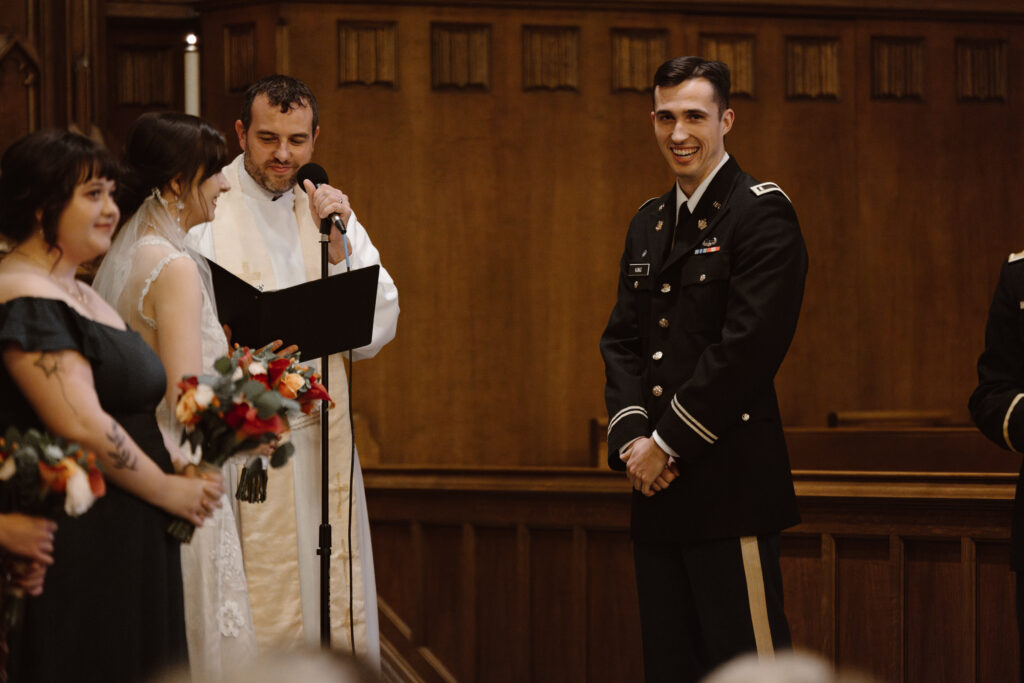 Groom smiling into the pews during his wedding ceremony