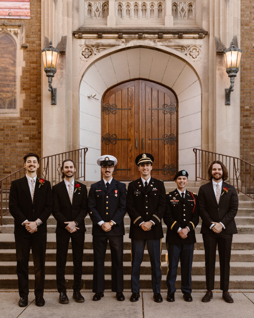 Groom and his groomsmen, most in uniform, lined up in front of their church
