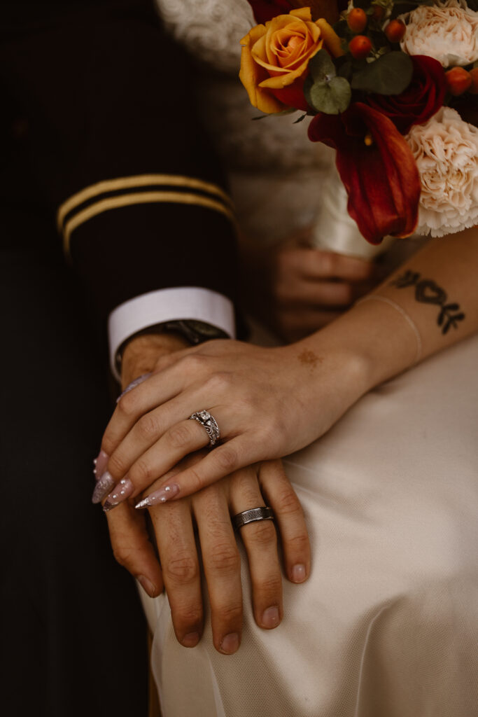 Bride and groom's hands, one on top of the other, highlighting their wedding rings