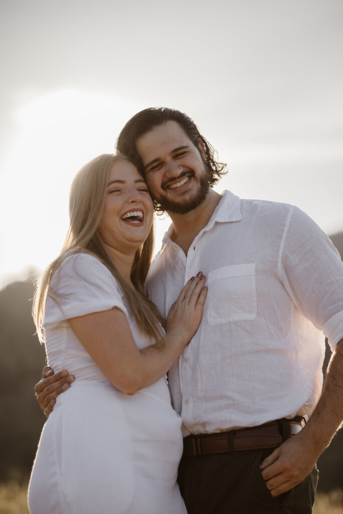 Couple laughing together during their golden hour engagement photos at Chautauqua Park in Boulder, Colorado.