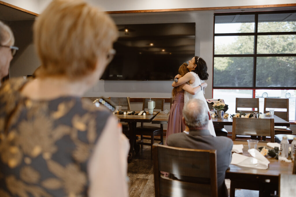 Bride hugging bridesmaid after emotional wedding toast at Walnut Creek Golf Preserve reception in Westminster Colorado captured by Colorado wedding photographer.