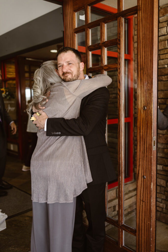Groom hugging his mother as she walks into the reception