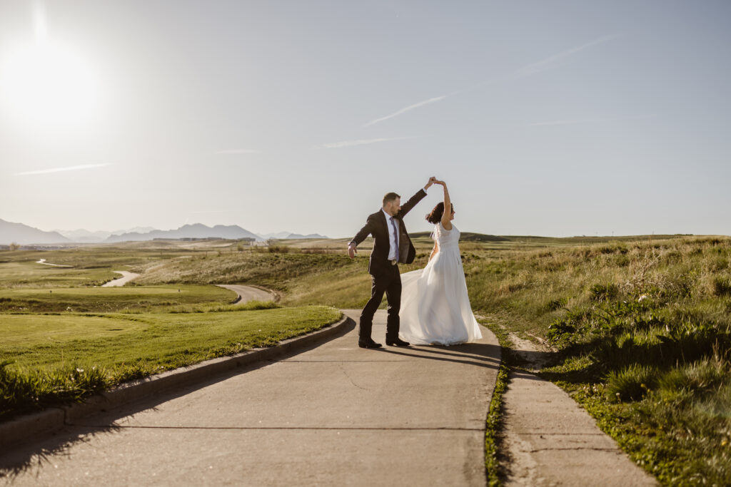Bride and groom dancing at sunset on golf course at Walnut Creek Golf Preserve wedding in Westminster Colorado with mountain views by Colorado wedding photographer.