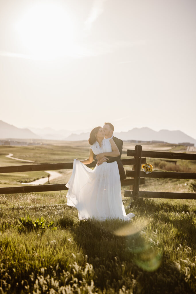 Bride and groom embracing at sunset with mountain views at Walnut Creek Golf Preserve wedding in Westminster Colorado captured by Colorado wedding photographer.