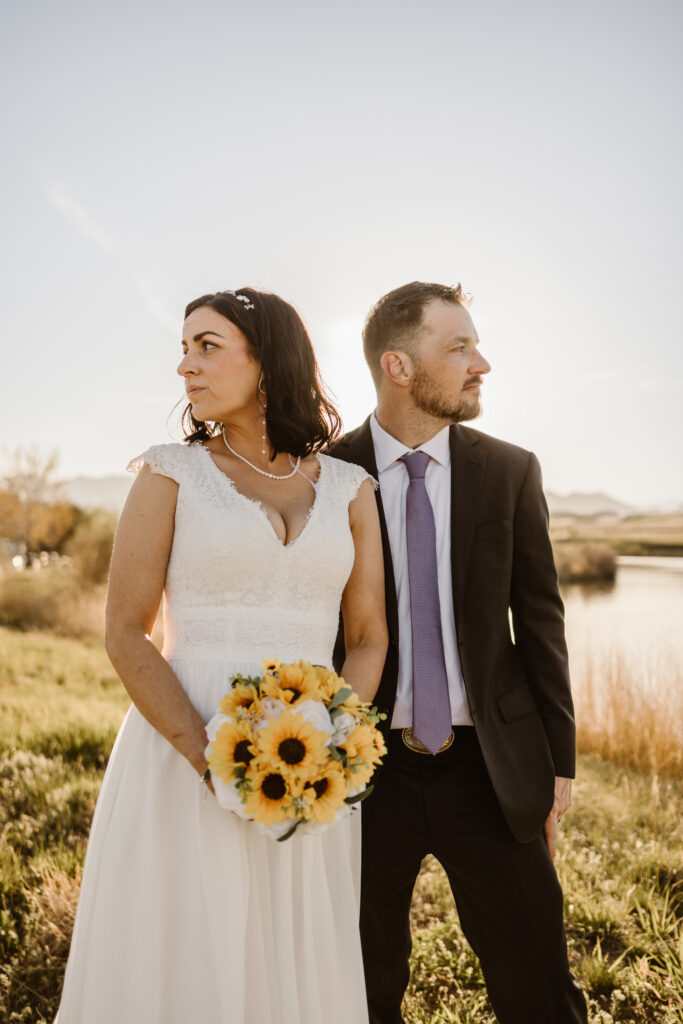 Bride holding sunflower bouquet with groom beside her during golden hour wedding portraits at Walnut Creek Golf Preserve in Westminster Colorado by Colorado wedding photographer.