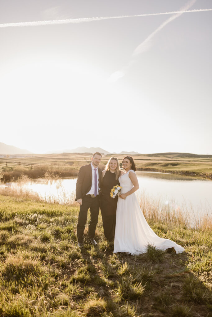 Bride and groom standing with their Colorado wedding photographer during golden hour portraits at Walnut Creek Golf Preserve in Westminster Colorado.